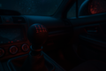 “Close-up of a black 6-speed JDM shift knob installed in a Subaru WRX interior at night. Subtle red and blue lighting, carbon fiber center console, rain-speckled window reflections, cinematic touge-inspired scene.”